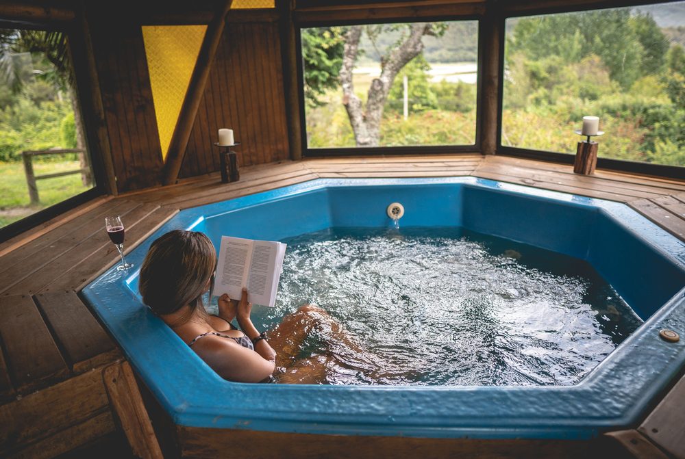 Jacuzzi de madera con ventanales hacia el bosque y el lago
